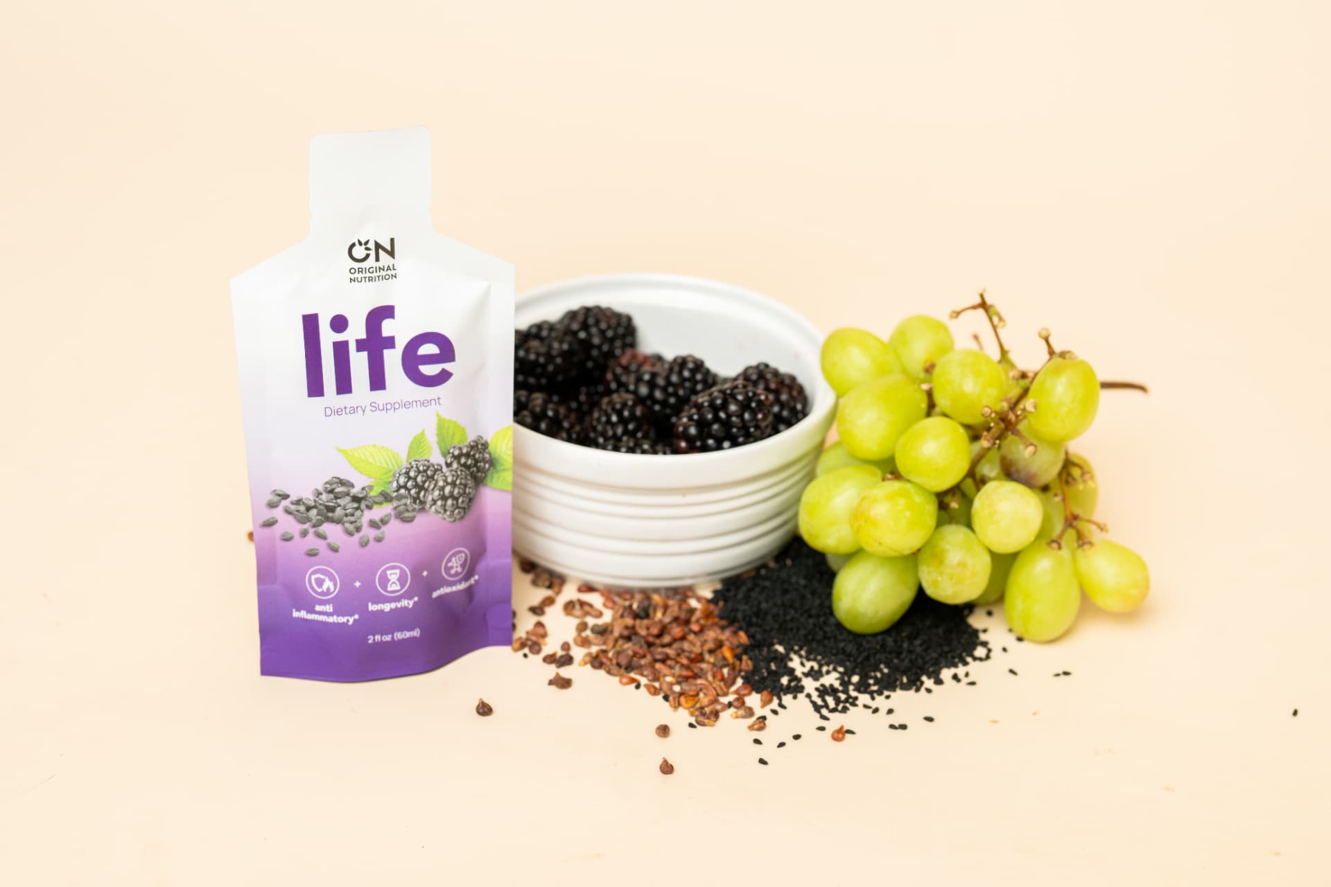 Original Nutrition 'Life' supplement pouch with blackberries, grapes, and seeds on a beige surface